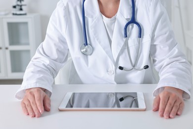 Photo of Doctor with tablet at table in clinic, closeup view