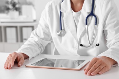 Photo of Doctor with tablet at table in clinic, closeup view