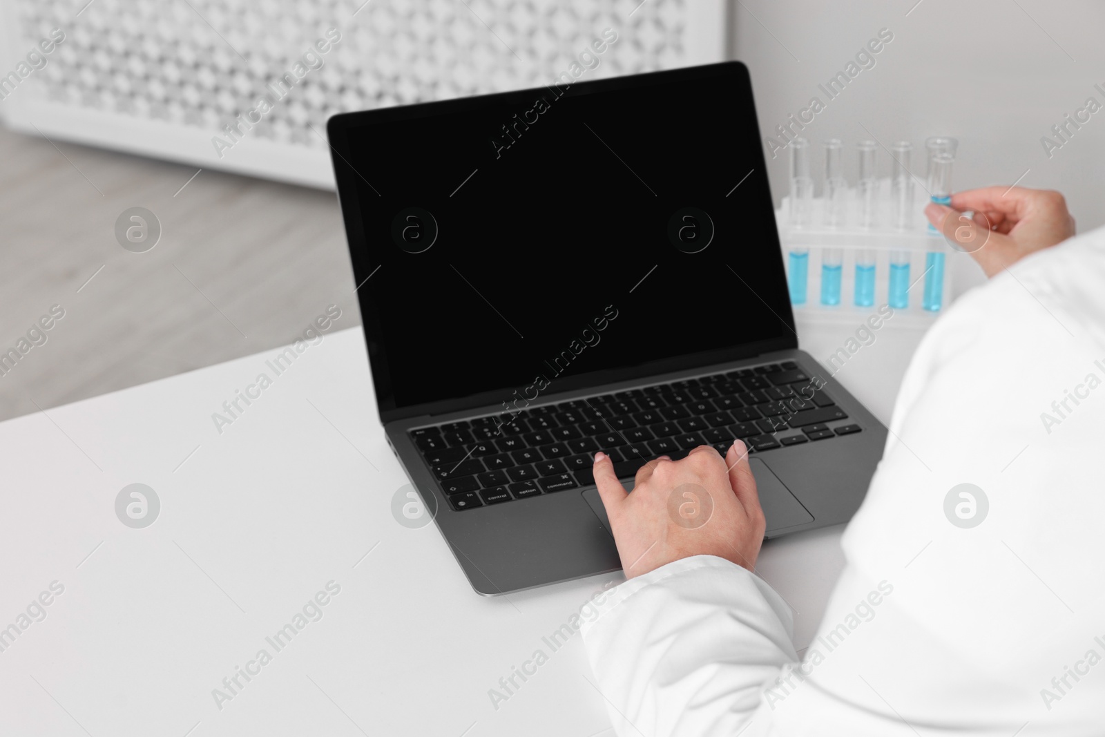 Photo of Doctor with laptop at table in clinic, closeup view