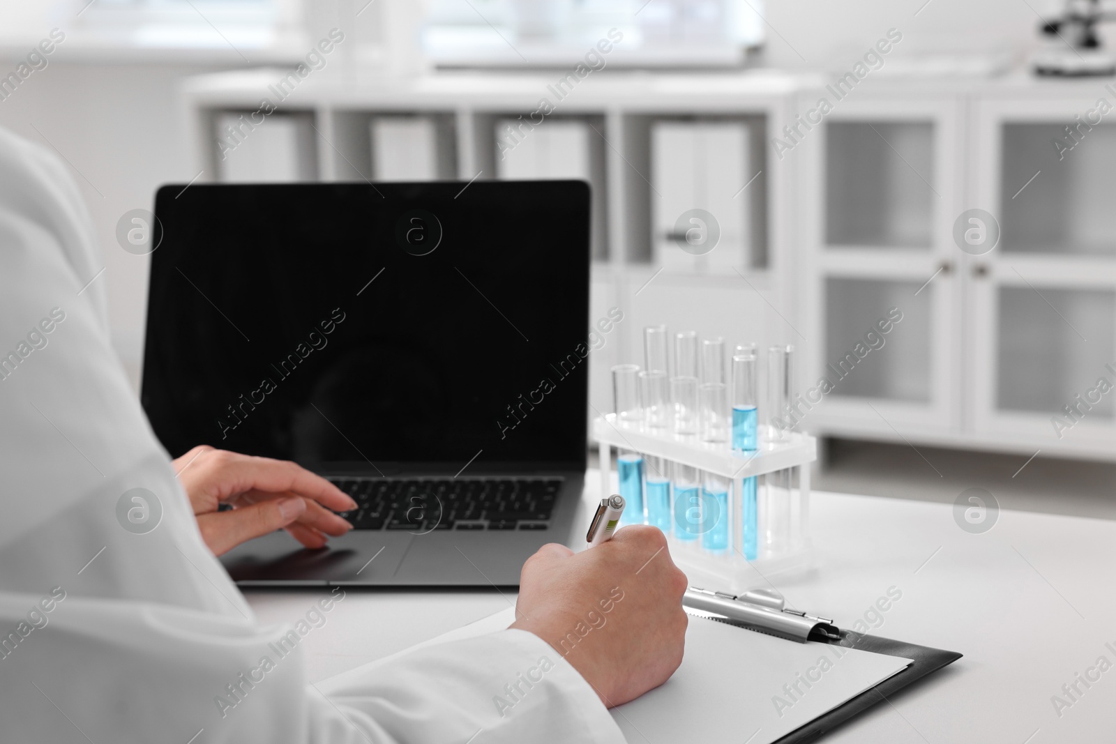 Photo of Doctor with laptop at table in clinic, closeup view