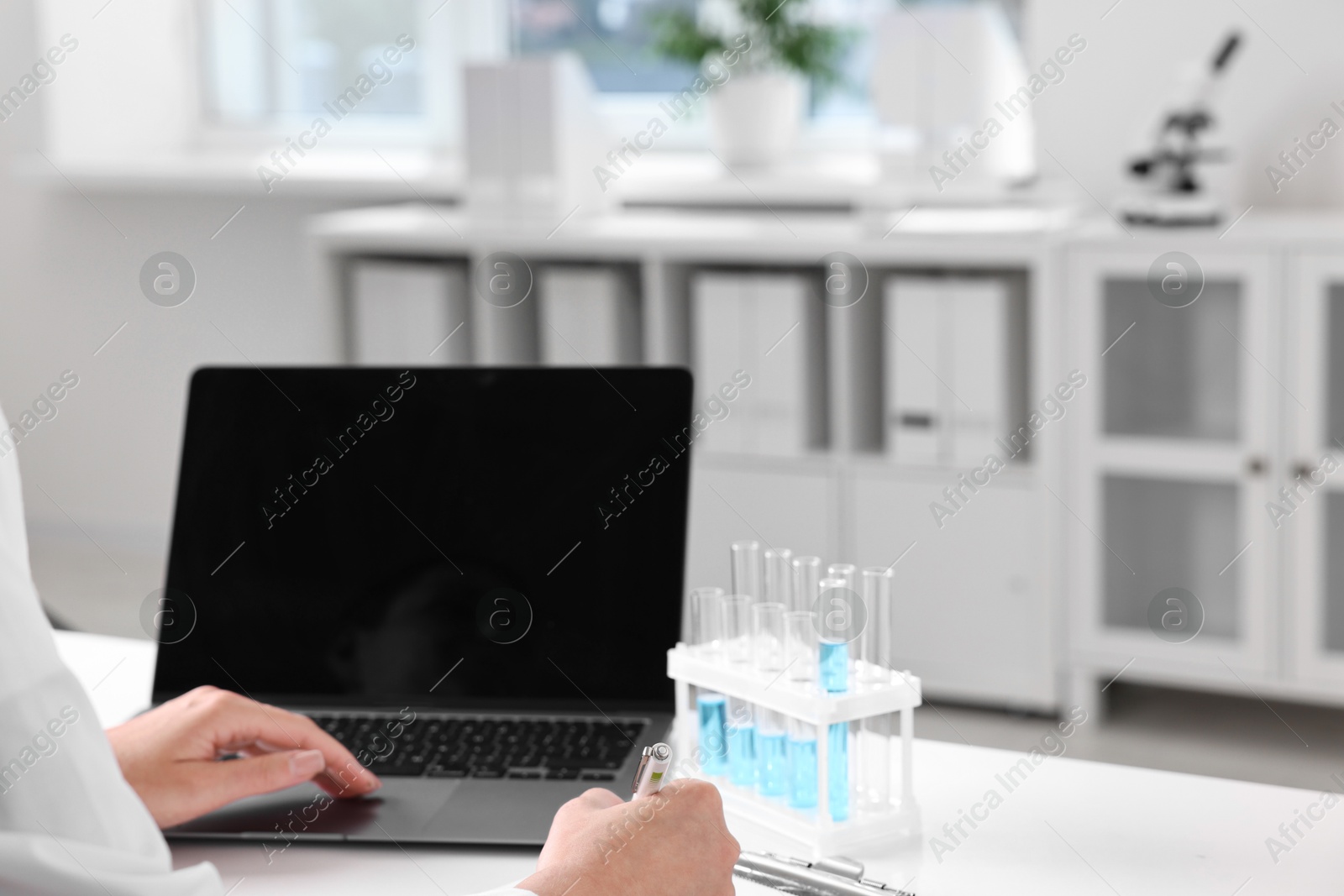 Photo of Doctor with laptop at table in clinic, closeup view