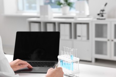 Photo of Doctor with laptop at table in clinic, closeup view