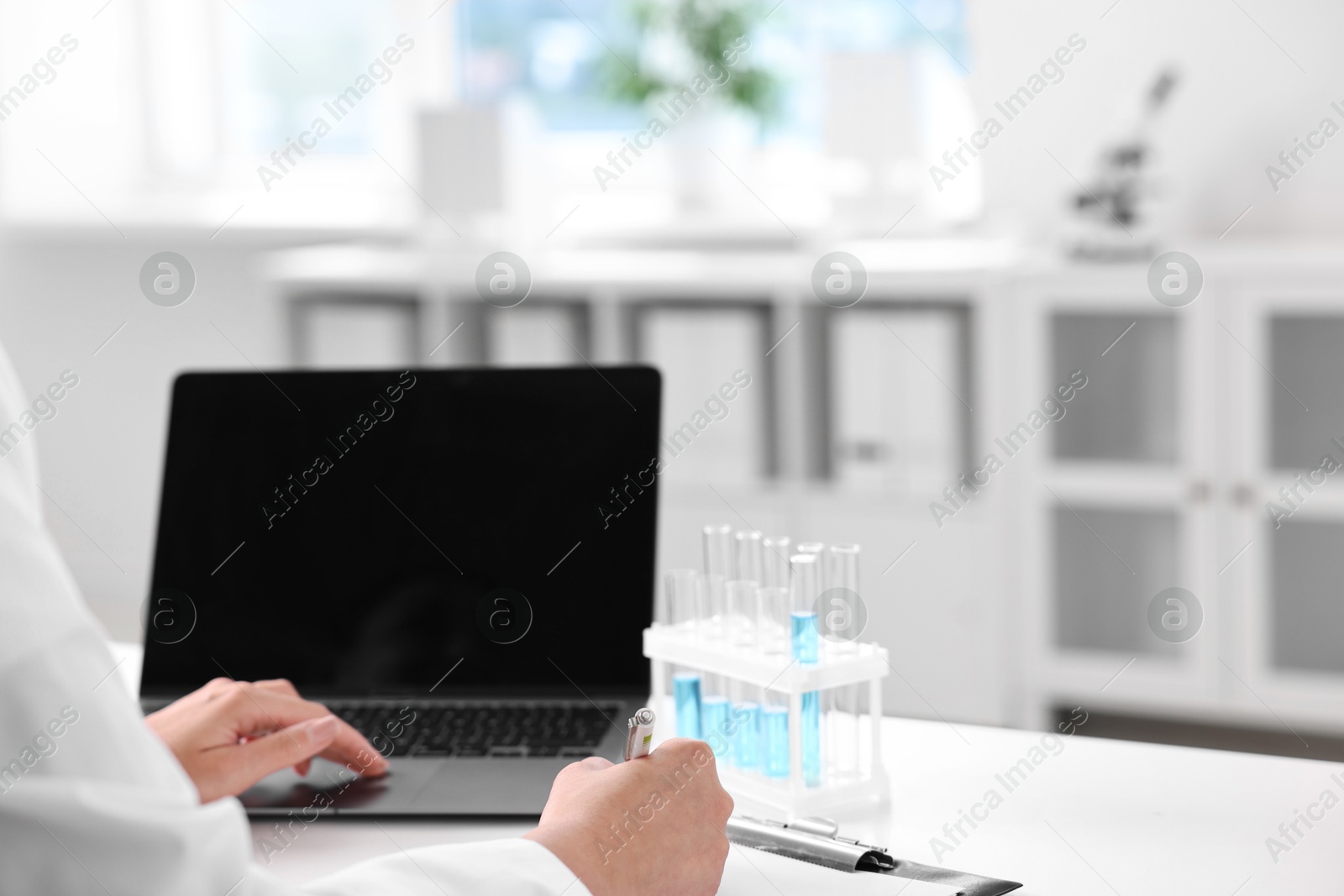 Photo of Doctor with laptop at table in clinic, closeup view