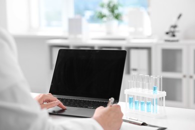 Photo of Doctor with laptop at table in clinic, closeup view