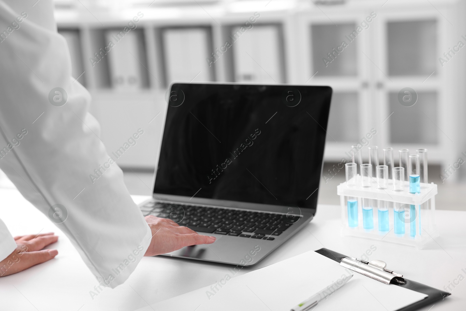 Photo of Doctor with laptop at table in clinic, closeup view