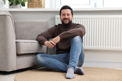 Happy man near heating radiator at home