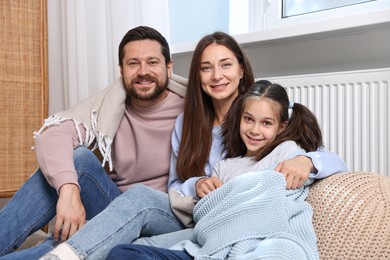 Happy family near heating radiator at home