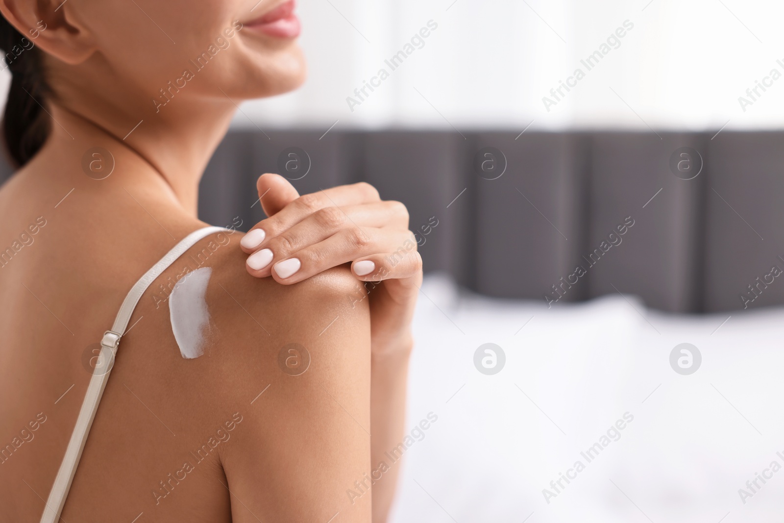 Photo of Body care. Woman applying cream onto shoulder indoors, back view. Space for text