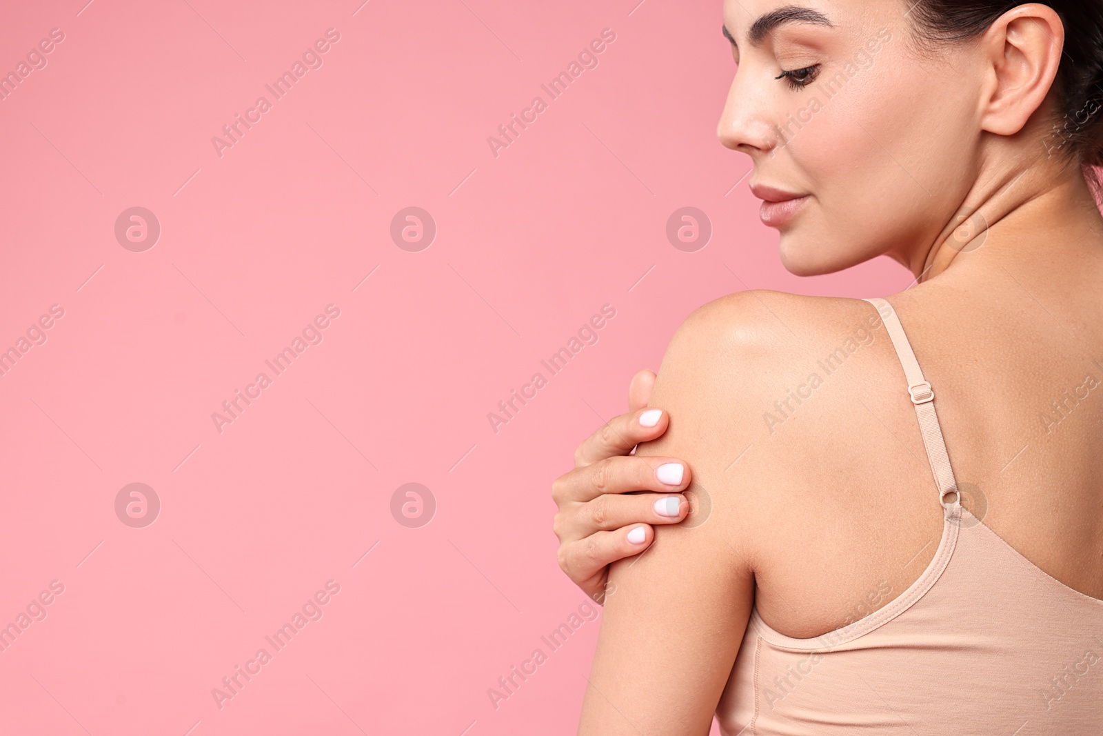 Photo of Beautiful woman with perfect skin on pink background, back view with space for text. Body care