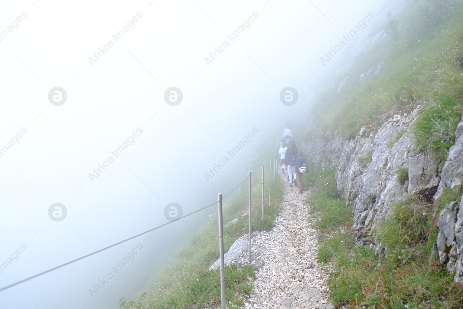 Photo of Group of tourists hiking in foggy mountains