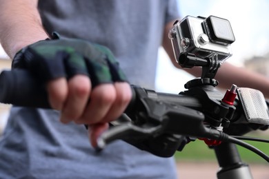 Man riding bicycle with modern action camera outdoors, closeup