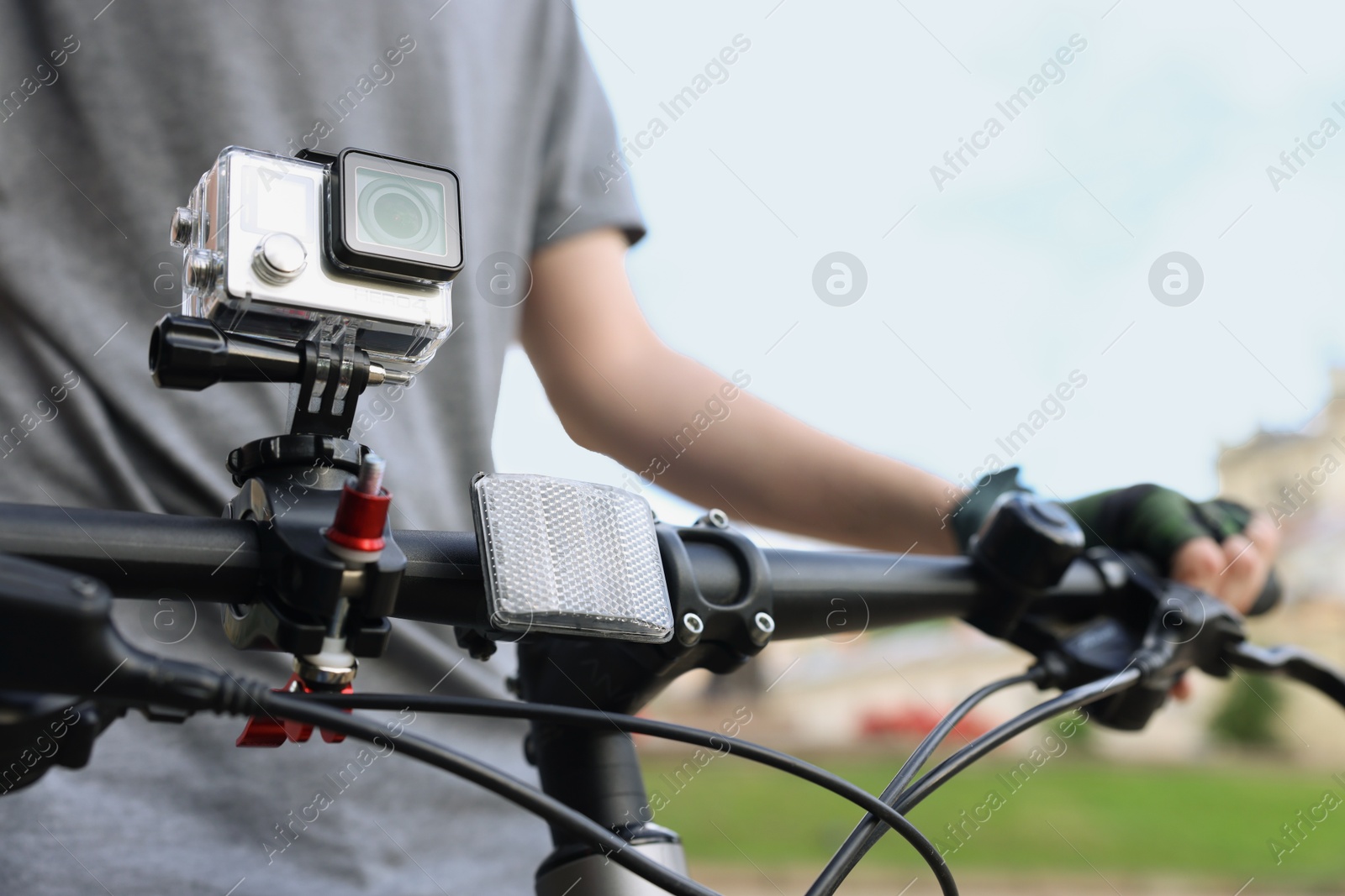 Photo of Man riding bicycle with modern action camera outdoors, closeup