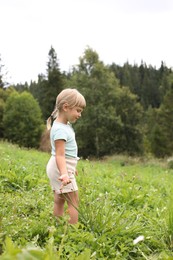 Cute little girl walking at green meadow. Enjoying beautiful nature