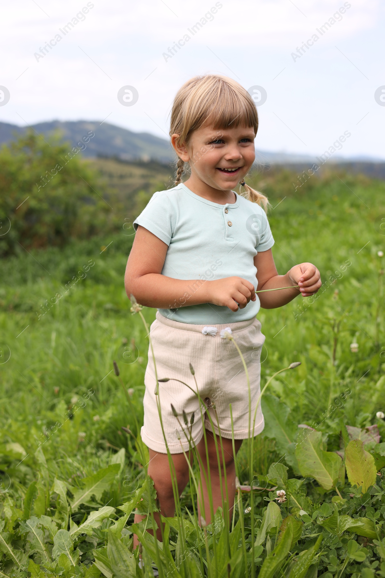 Photo of Happy little girl walking at green meadow. Enjoying beautiful nature