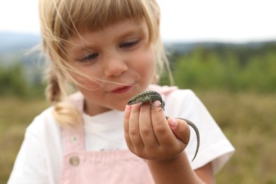 Photo of Little girl exploring lizard on blurred background. Enjoying beautiful nature