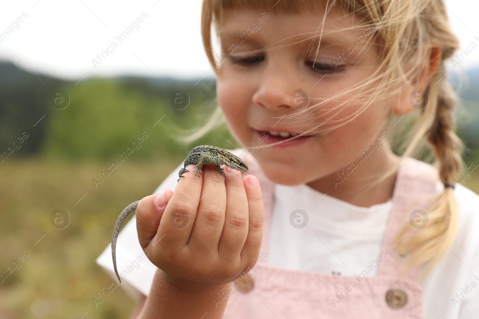 Photo of Little girl exploring lizard on blurred background. Enjoying beautiful nature