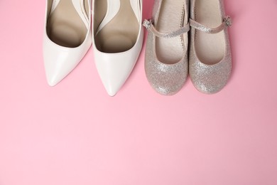 Photo of Big and small shoes on pink background, top view. Space for text