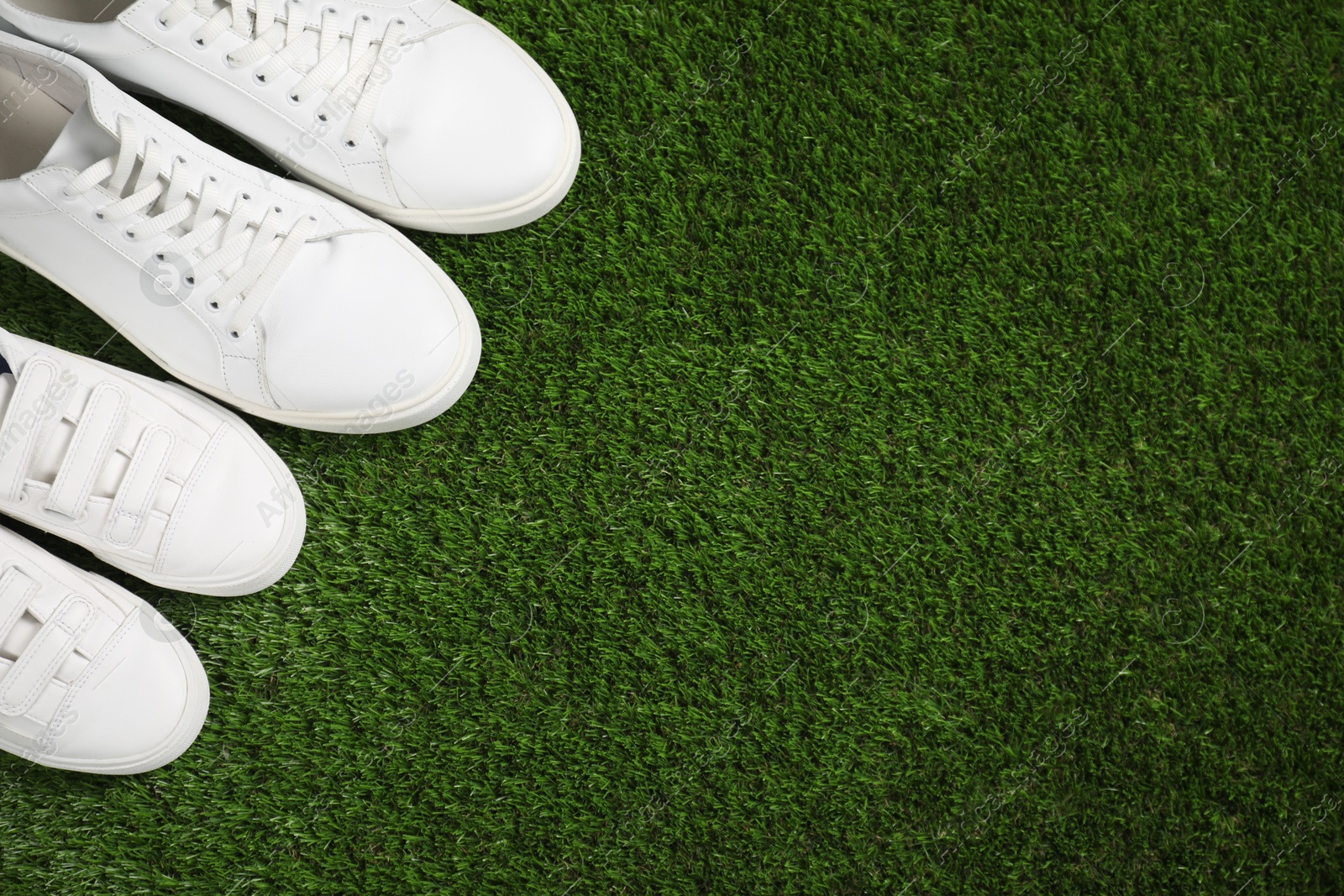 Photo of Big and small shoes on green grass, top view. Space for text