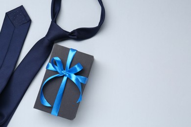 Photo of Happy Father's Day. Gift and tie on light background, flat lay. Space for text