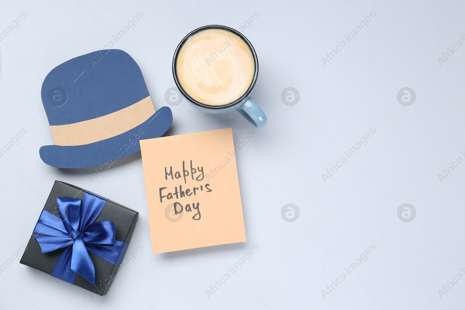 Photo of Greeting card with phrase Happy Father's Day, coffee, gift and paper hat on light background, flat lay. Space for text