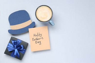 Photo of Greeting card with phrase Happy Father's Day, coffee, gift and paper hat on light background, flat lay. Space for text