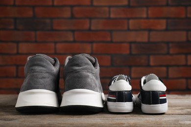 Photo of Big and small sneakers on wooden surface