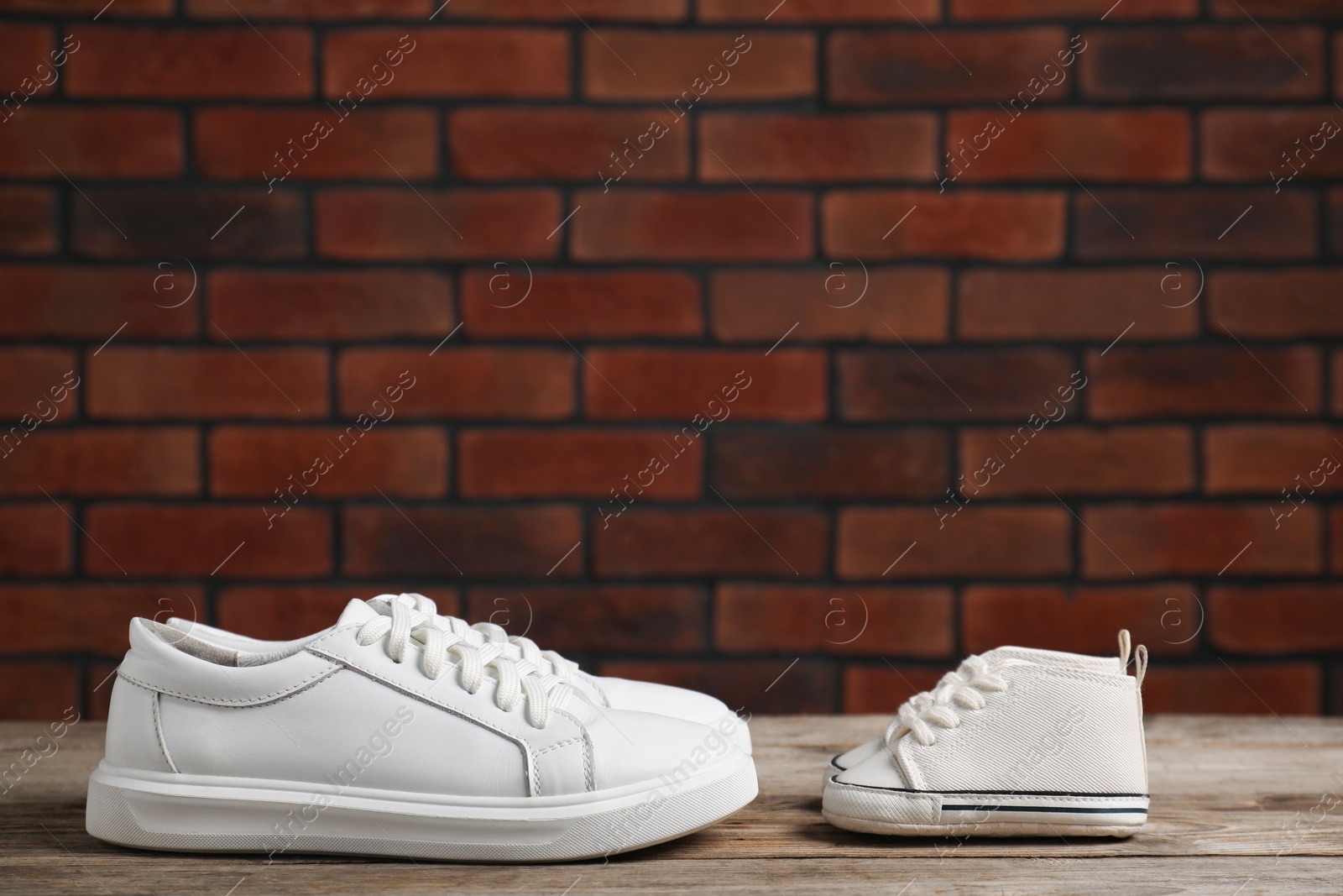 Photo of Big and small sneakers on wooden surface