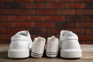 Photo of Big and small sneakers on wooden surface