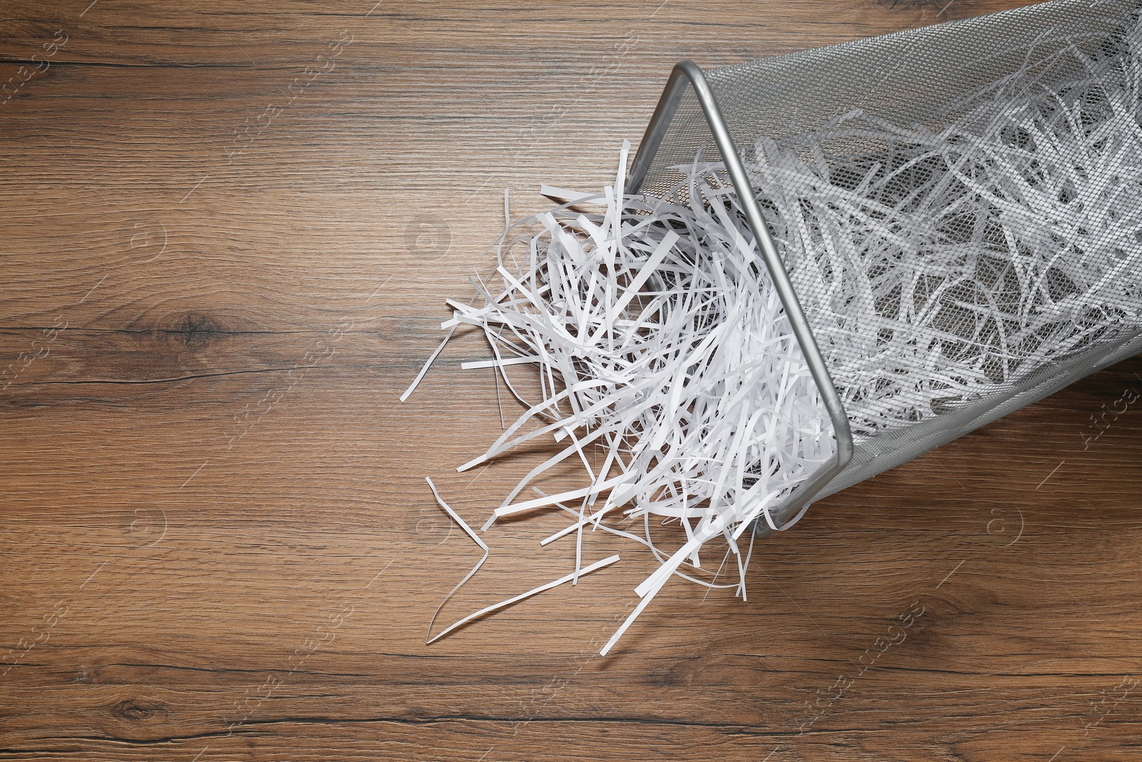 Photo of Shredded paper strips in trash bin on wooden table, top view. Space for text