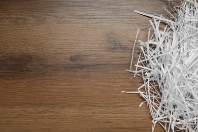 Photo of Shredded paper strips on wooden table, top view. Space for text