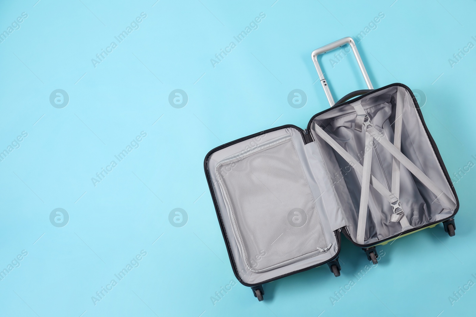 Photo of Open empty suitcase on light blue background, top view. Space for text