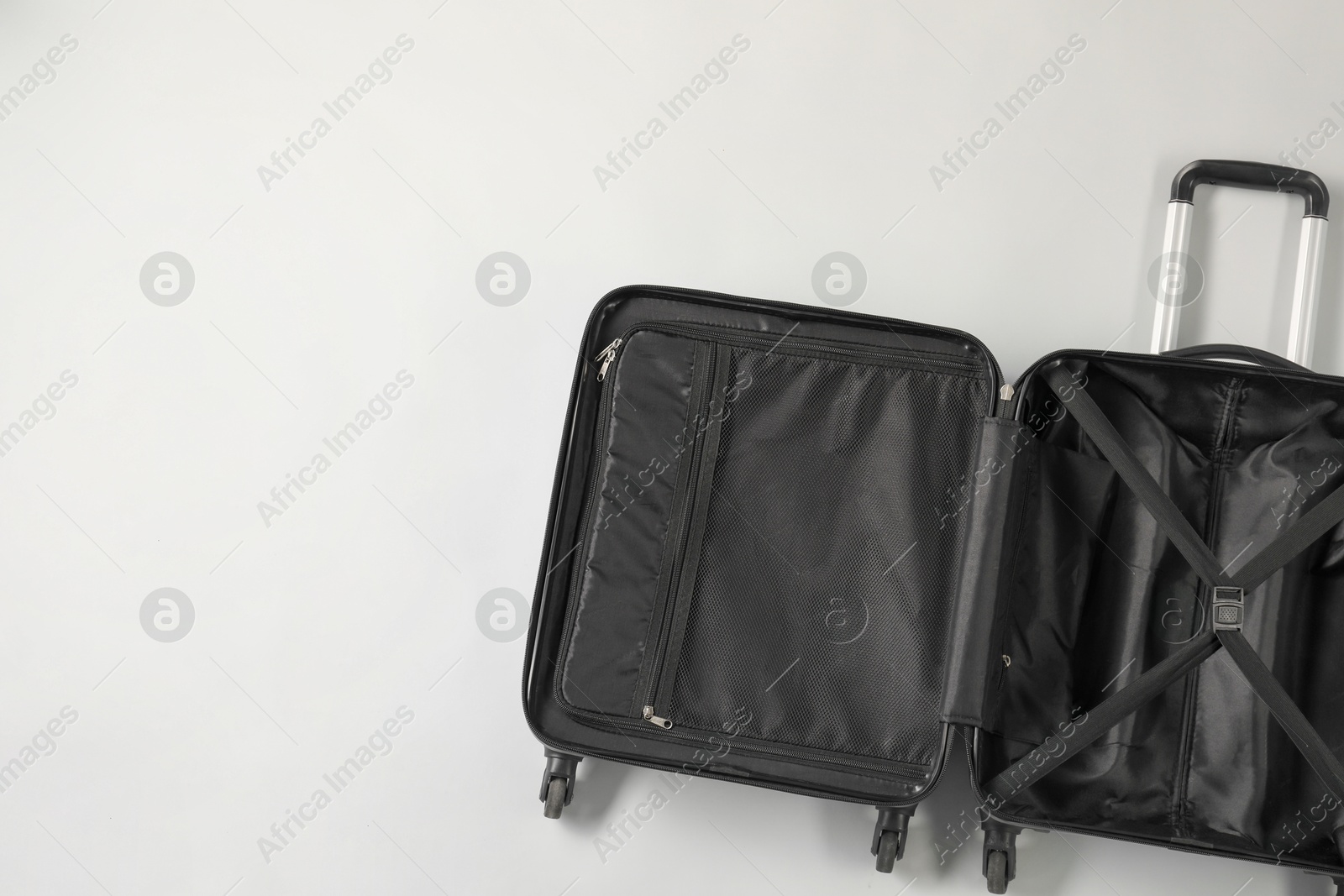 Photo of Open empty suitcase on light grey background, top view. Space for text