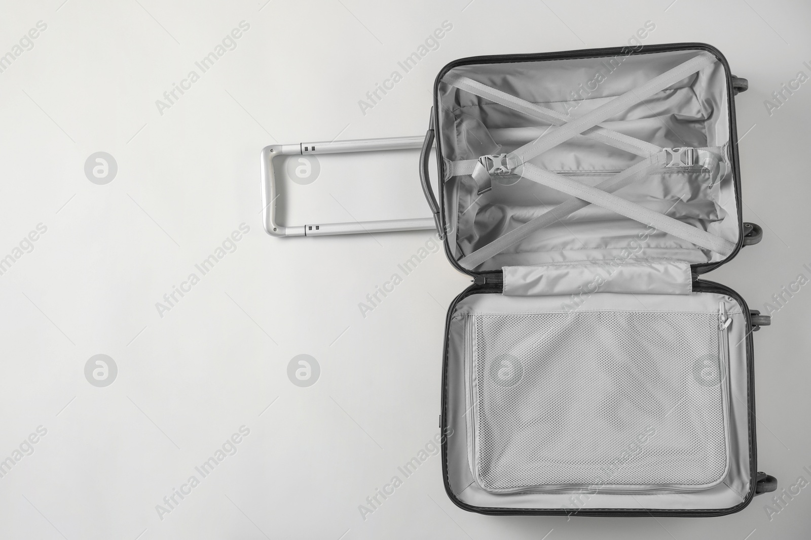 Photo of Open empty suitcase on light grey background, top view. Space for text