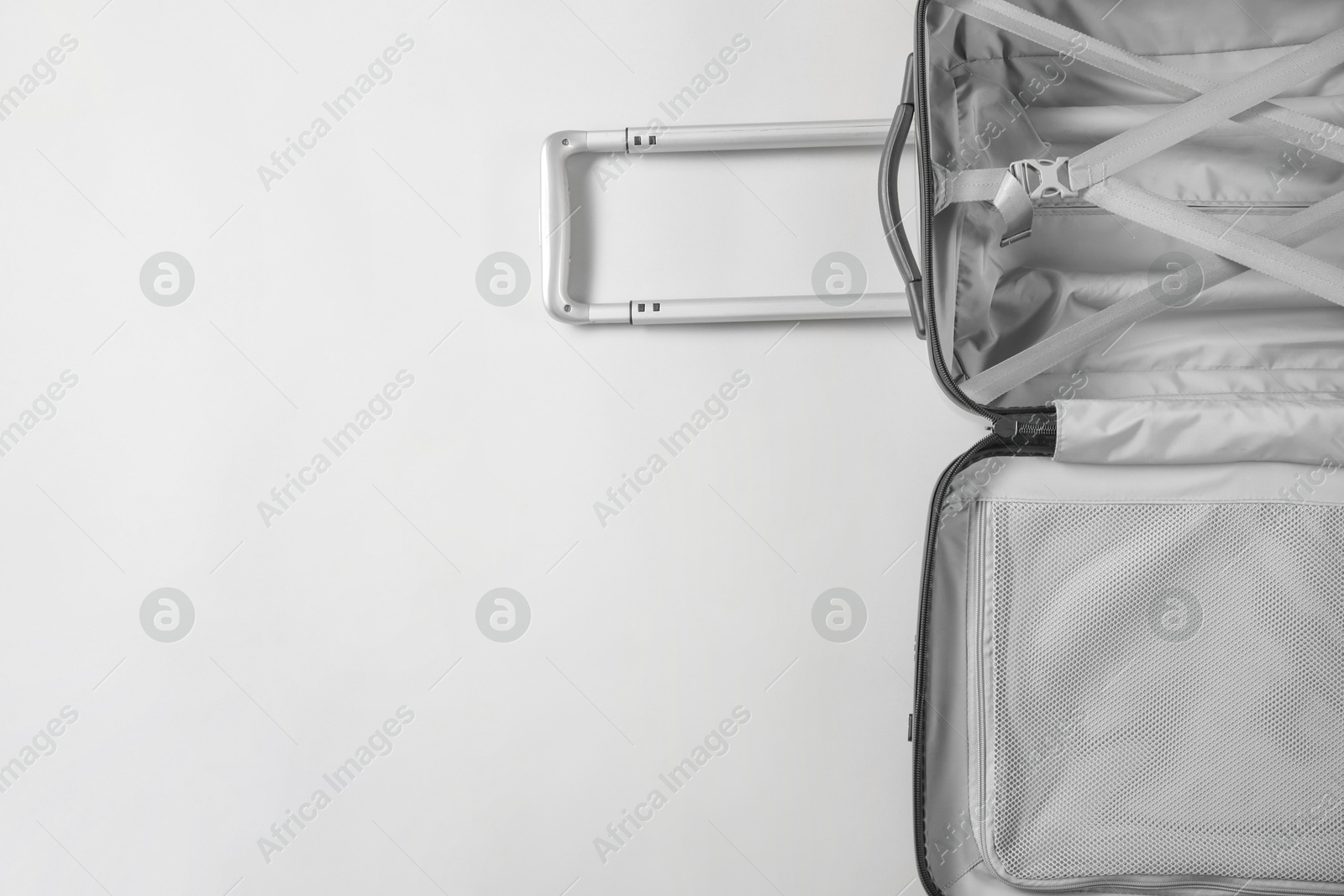 Photo of Open empty suitcase on light grey background, top view. Space for text