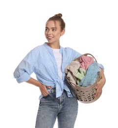 Happy young housewife with basket full of laundry on white background