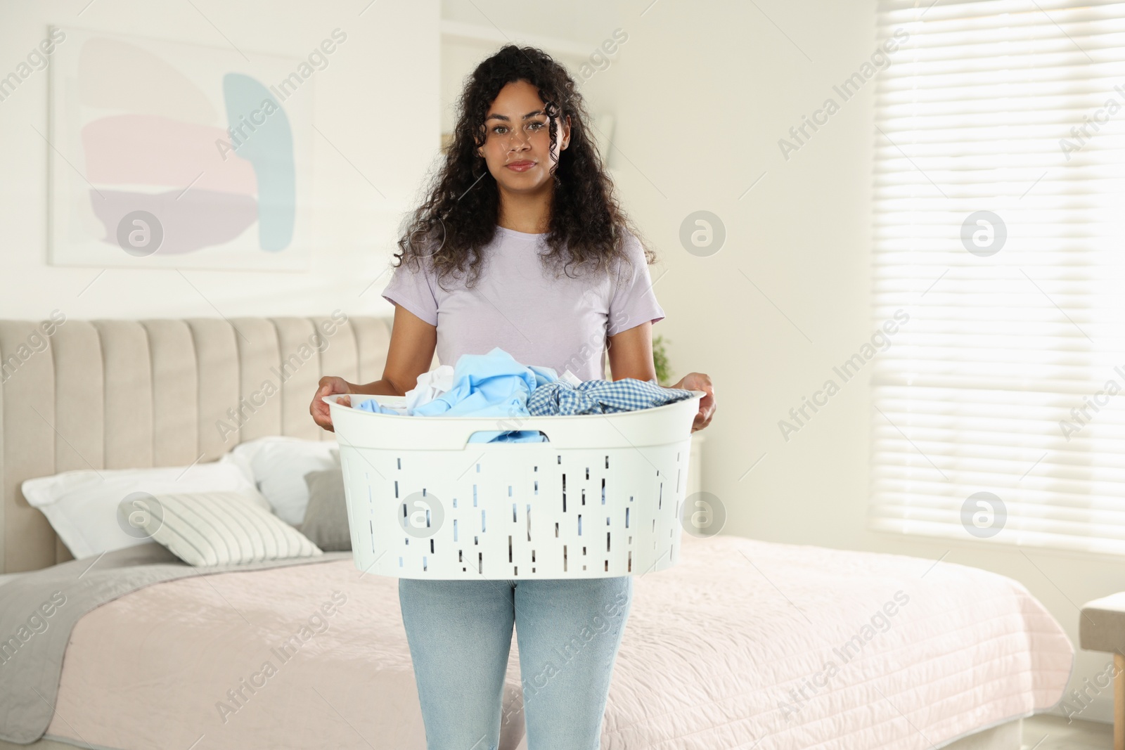 Photo of Woman with basket full of laundry in bedroom