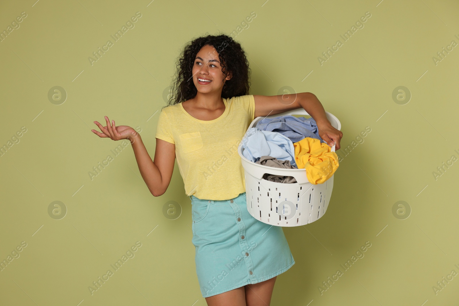 Photo of Happy woman with basket full of laundry on olive background