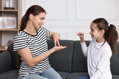 Woman and her daughter using sign language for communication at home