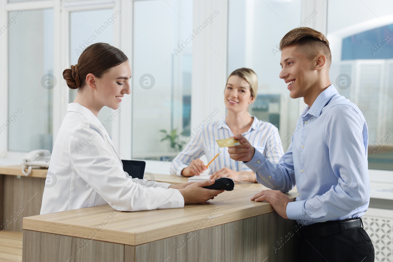 Photo of Receptionist taking payment from client via terminal at hospital