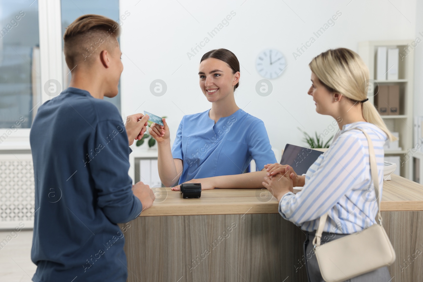 Photo of Receptionist taking payment from client via terminal at hospital