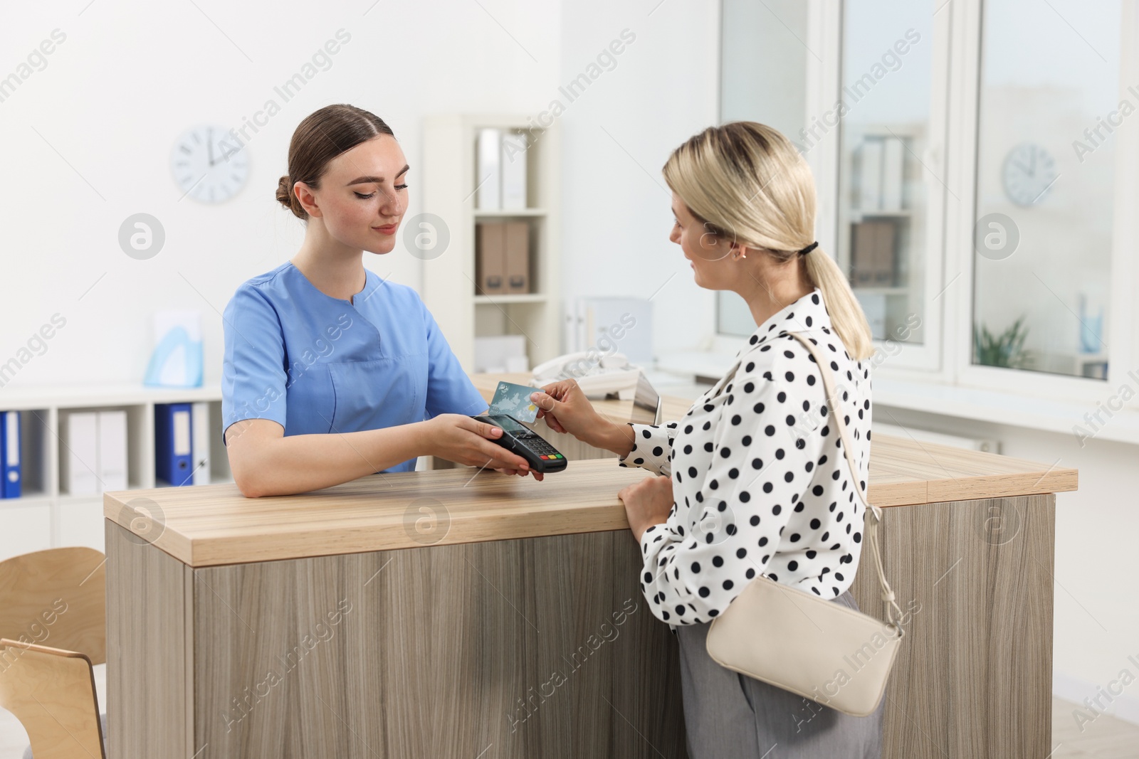 Photo of Receptionist taking payment from client via terminal at hospital