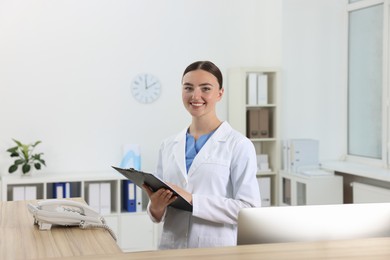 Professional receptionist working at wooden desk in hospital