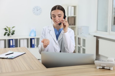 Professional receptionist working at wooden desk in hospital