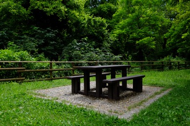 Photo of Empty wooden picnic table with benches in park on sunny day