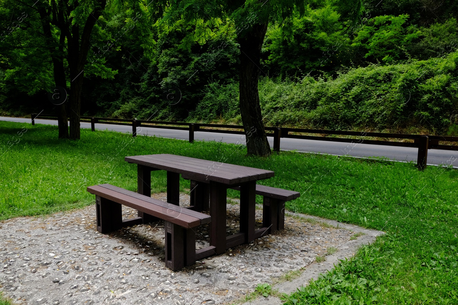 Photo of Empty wooden picnic table with benches in park on sunny day