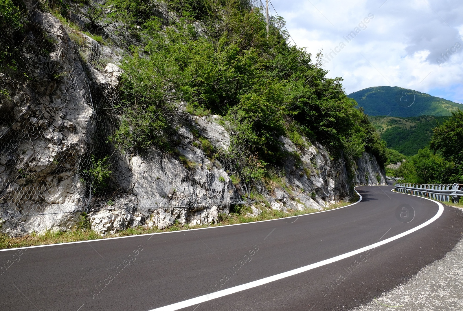 Photo of Picturesque view of rocky cliff and asphalt road in mountains