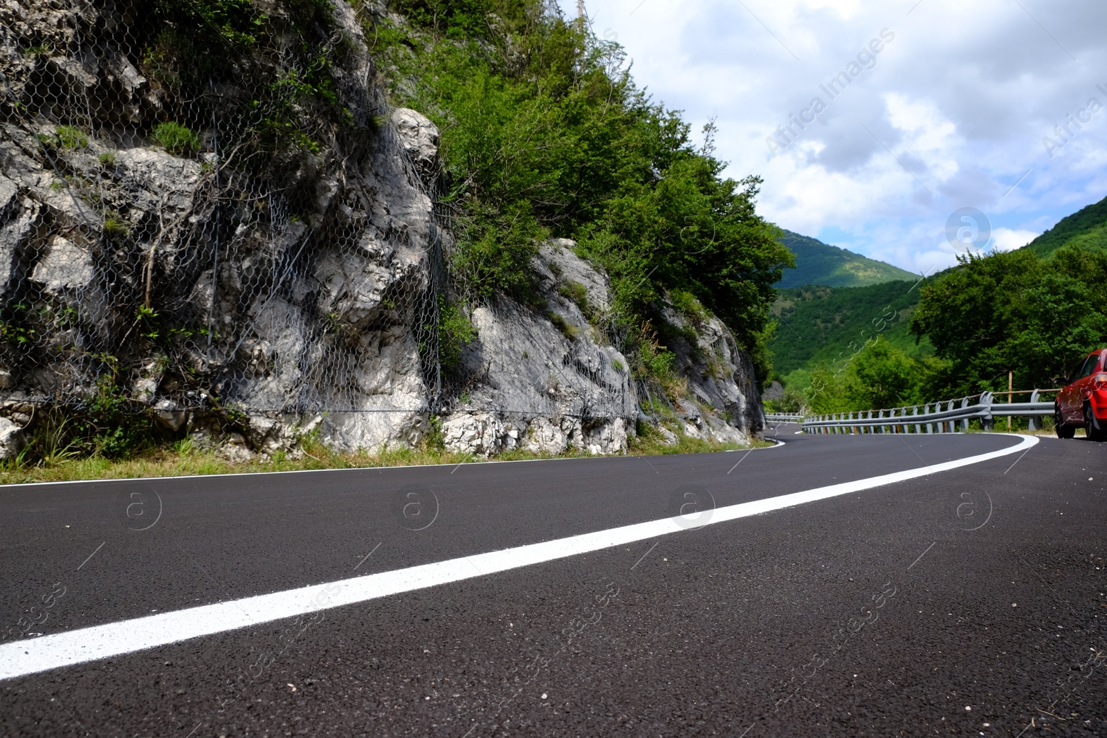 Photo of Picturesque view of rocky cliff and asphalt road in mountains