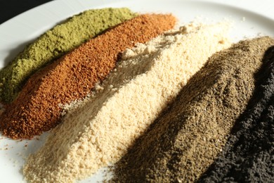 Photo of Different superfood powders on plate, closeup view