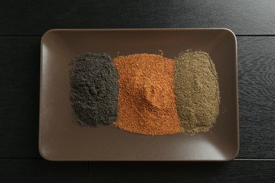 Different superfood powders on black wooden table, top view