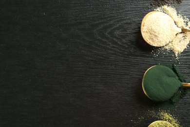 Photo of Different superfood powders in spoons on black wooden table, flat lay. Space for text